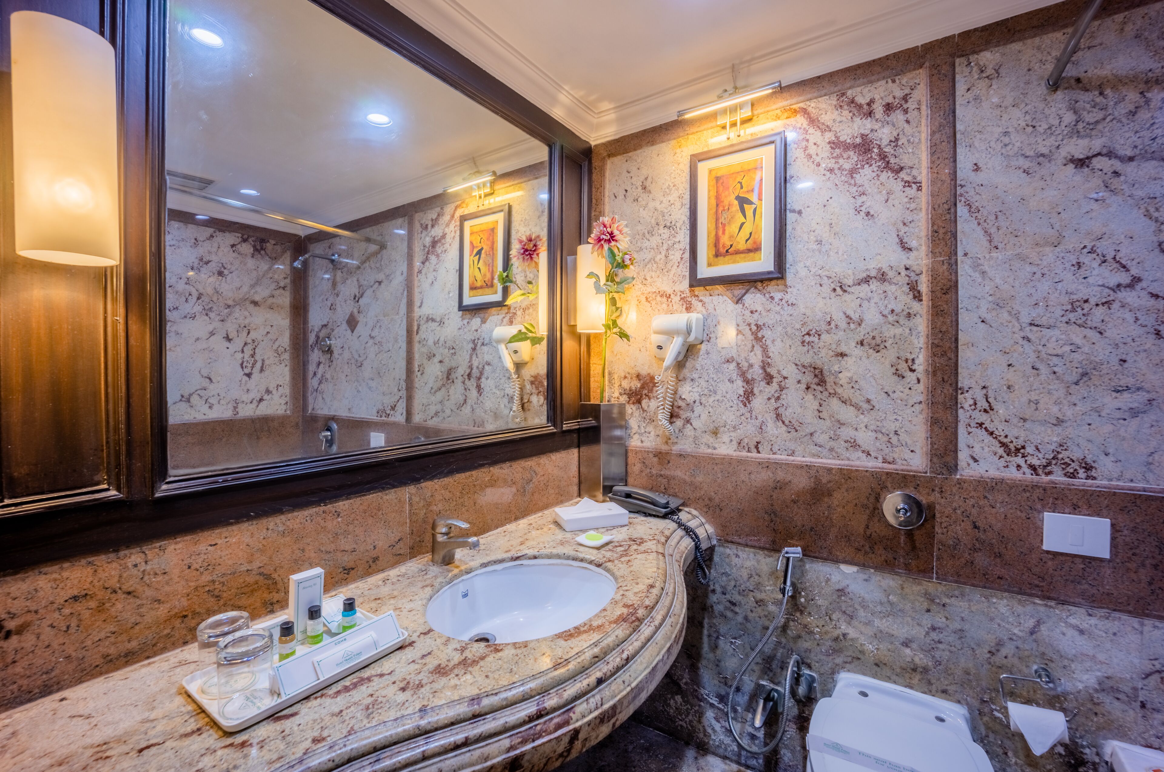 A marble bathroom with a large mirror, a sink, and a shower.
