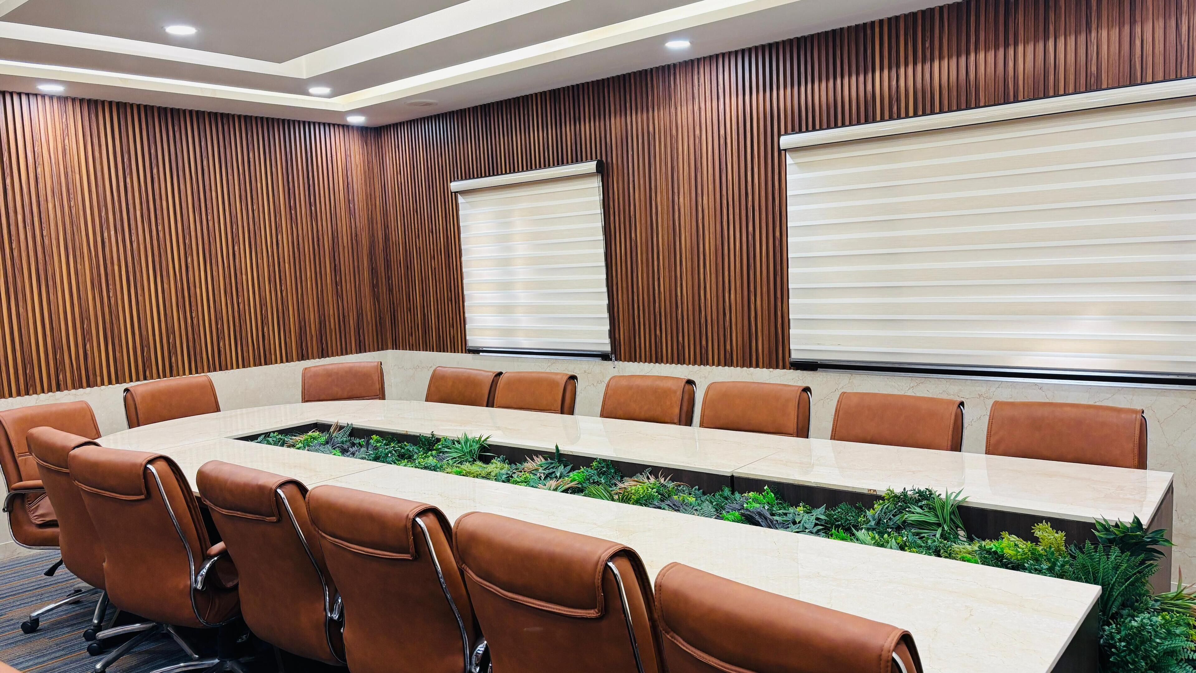 A conference room with a long table, brown leather chairs, and a wooden panel wall.