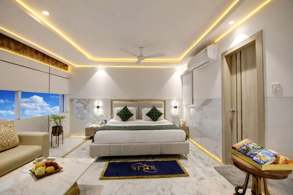 A modern bedroom with a large bed, bedside lamps, a ceiling fan, and a view of the sky through the window.