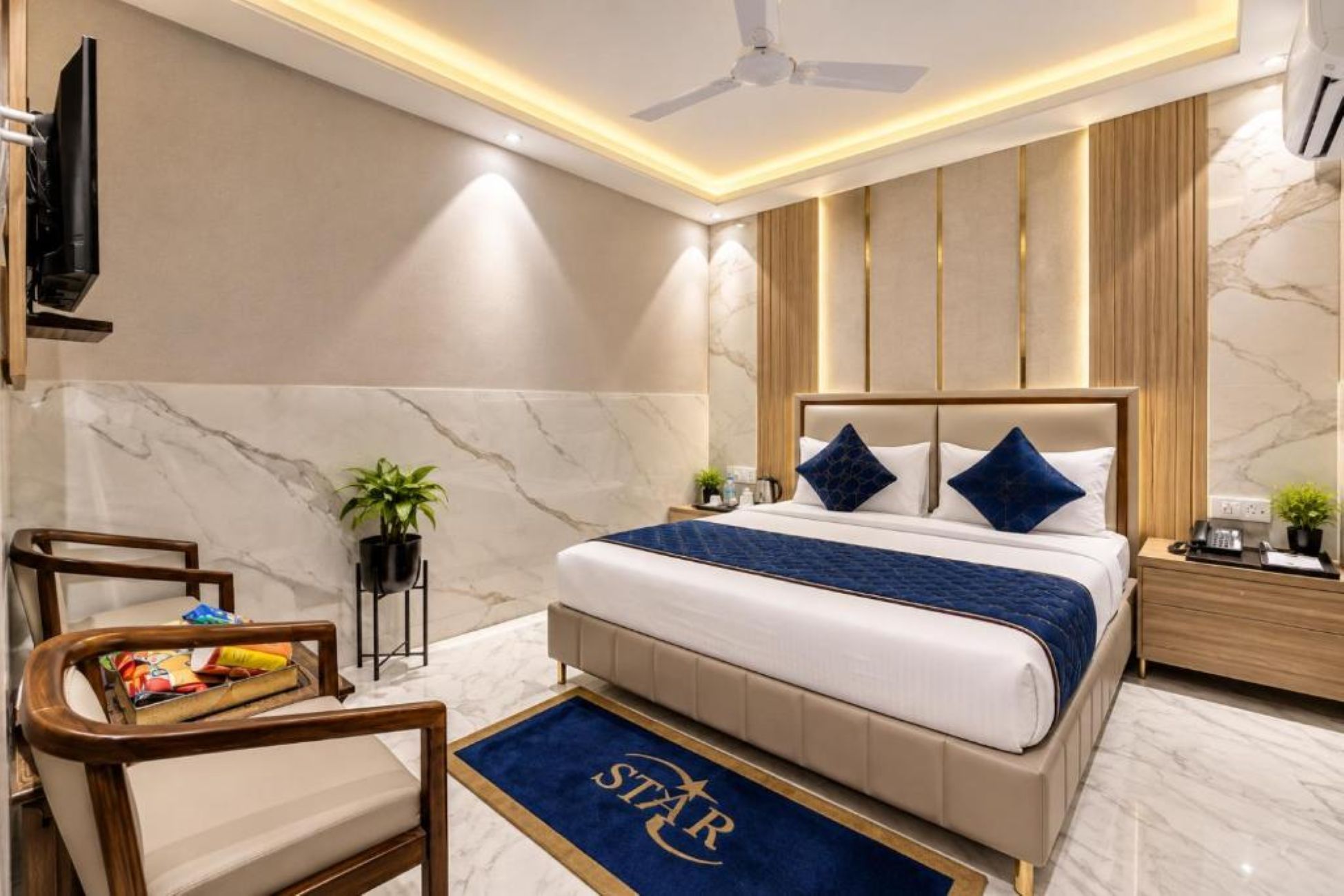 A hotel room with a bed, a desk, a chair, a television, and a ceiling fan.