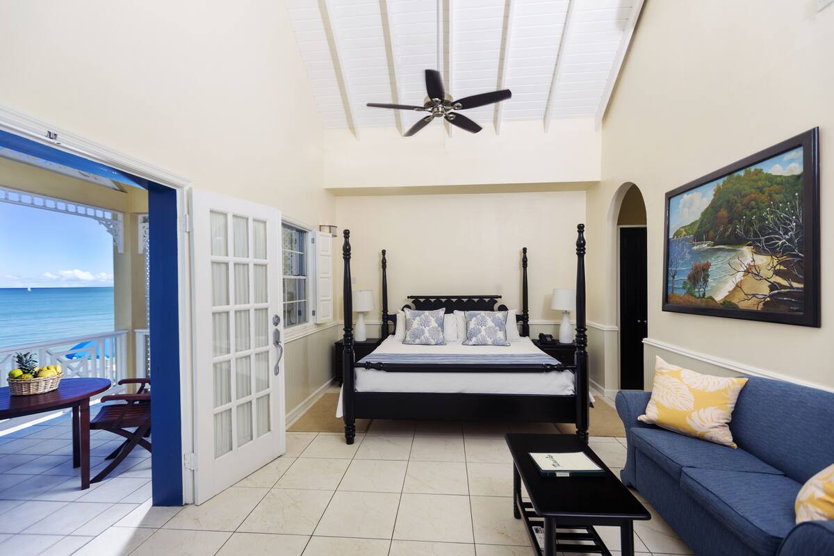 A bedroom with a bed, a sofa, a table, and a painting.