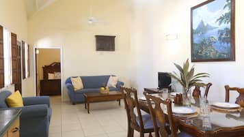 A living room with a blue sofa, a dining table set for two, and a large framed picture on the wall.