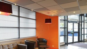 Un hall d’entrée moderne avec des canapés en cuir, une table basse ronde et un mur orné de motifs.