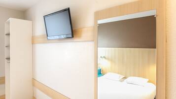 Una habitación de hotel con cama, televisión montada en la pared y armario.