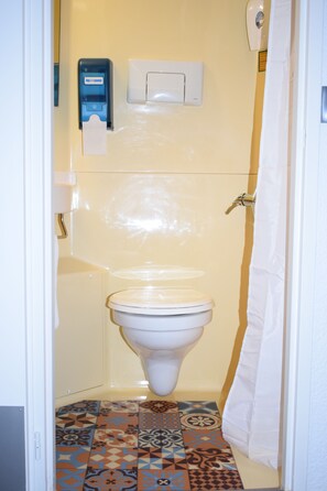Ein kleines Badezimmer mit Toilette, einem Händetrockner und einer Duschvorhang.