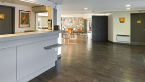 Una hall d'hotel moderna con reception, area ristorazione e parete decorata con una composizione di immagini.