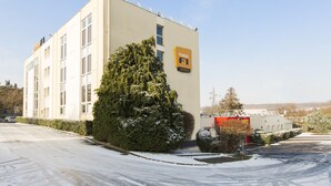 Edificio di un hotel con un cartello che indica 'hotel F1' e un'area di parcheggio ricoperta di neve.