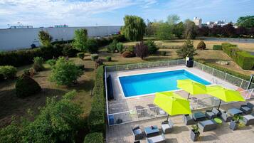 Una piscina con zona de terraza cercada, mobiliario exterior y vistas del paisaje circundante.