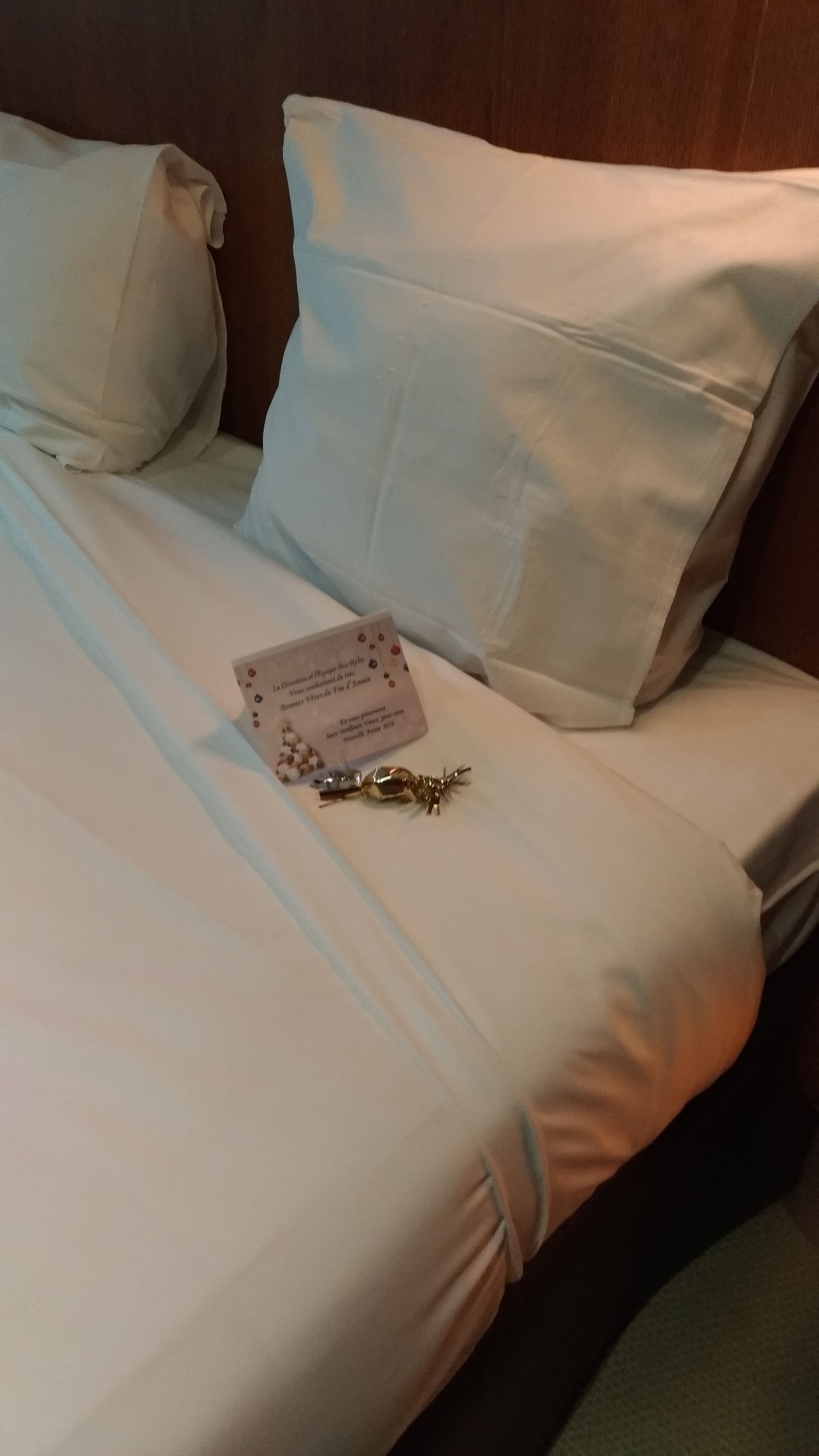 Een keurig opgemaakt bed met witte lakens, een klein kaartje en een decoratief voorwerp.