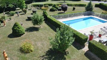 Un jardín cuidado con piscina, rodeado de setos bien recortados y diversas arbustos.