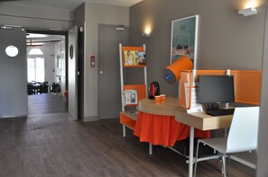 A modern office space with a desk, computer, and orange accents. - Ibis Styles Gien (Gien)