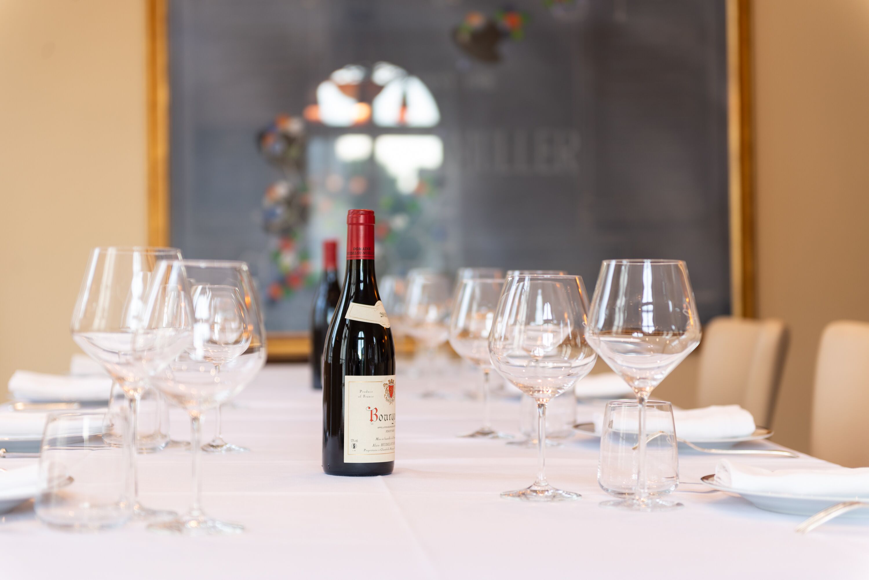 A dining table set with wine glasses and a bottle of wine, with a blurred background suggesting a restaurant setting.