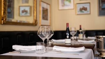 A dining table set with wine glasses, a bottle, and a silver pot.