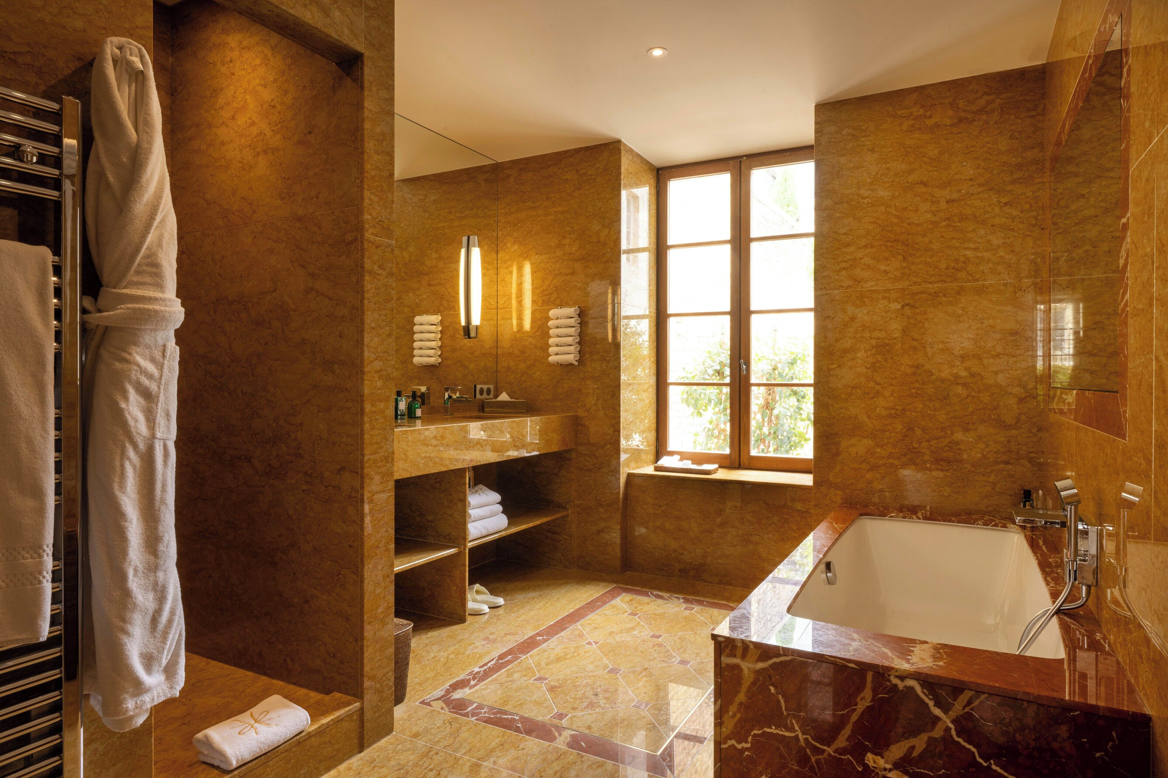 Une salle de bain moderne dotée d’une grande baignoire, d’un meuble-lavabo avec miroir et d’une fenêtre laissant entrer la lumière naturelle.