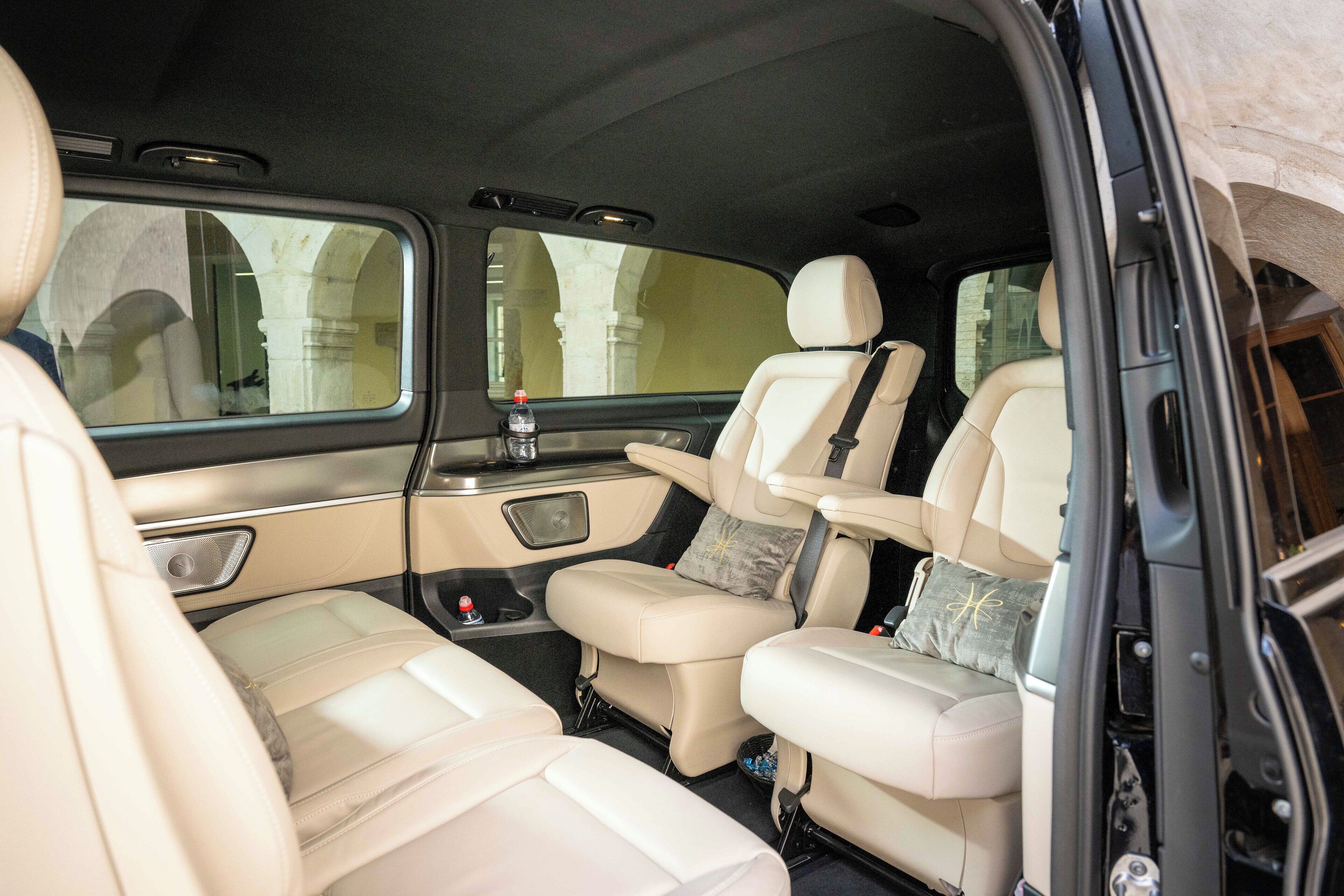 Un intérieur de voiture luxueux avec des sièges en cuir beige, une console centrale dotée de porte-gobelets et une bouteille d’eau posée sur le tableau de bord.