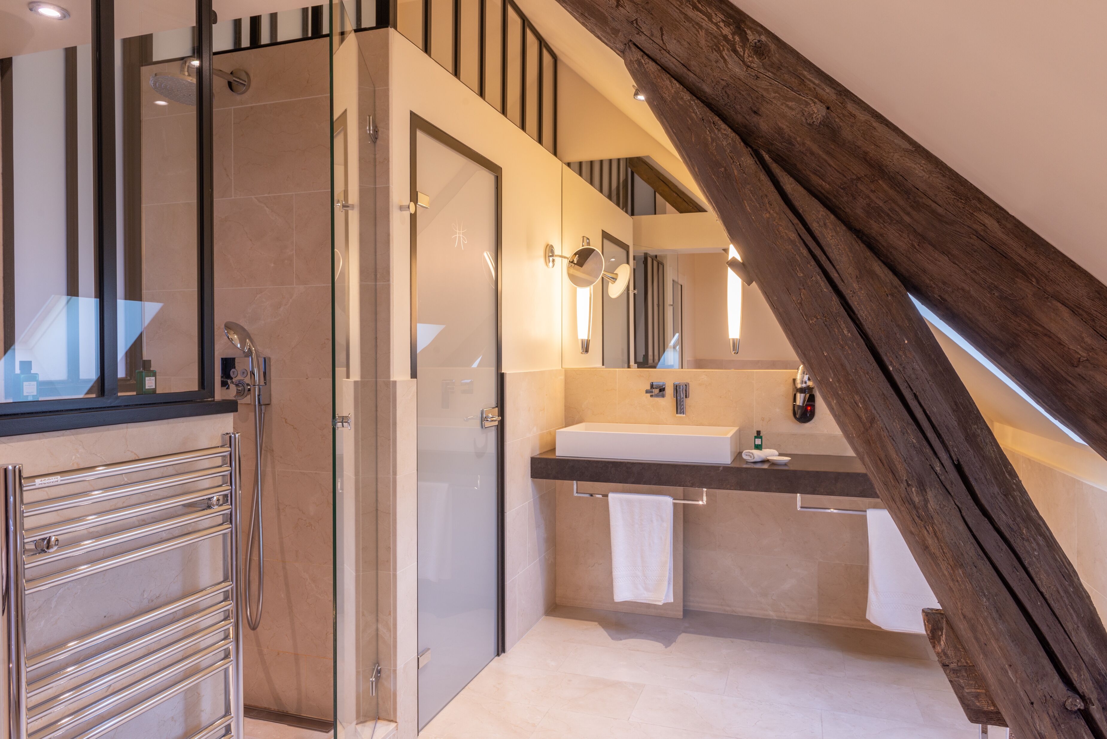 A modern bathroom with a glass shower, a sink, and a towel rack.