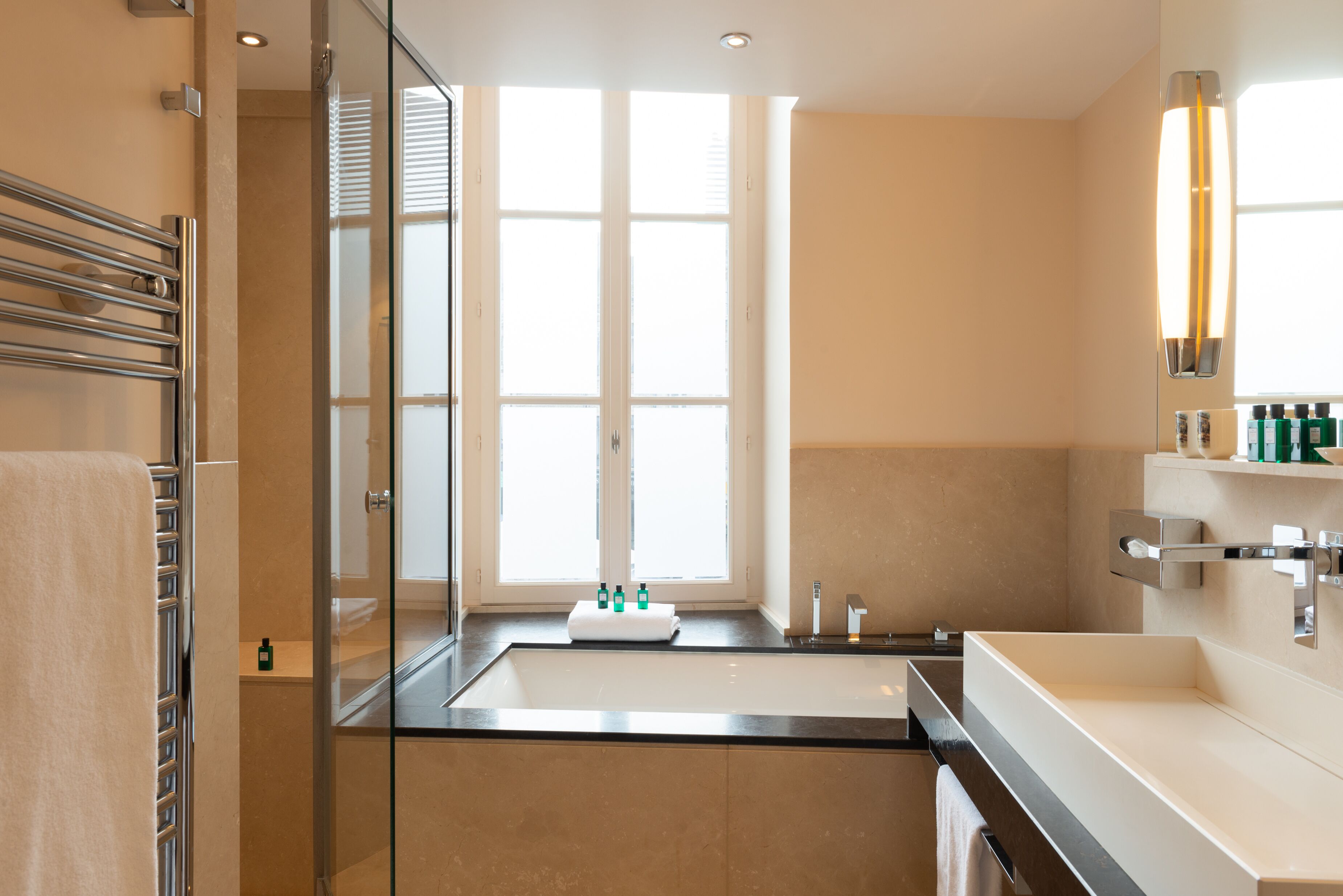 A modern bathroom with a large window, a glass shower enclosure, and a vanity with a sink and mirror.