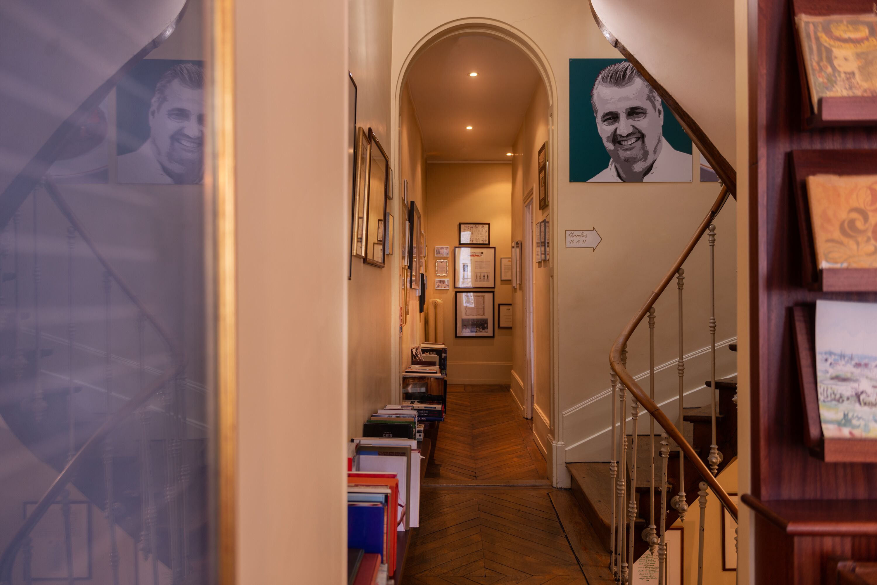 A hallway with bookshelves, framed pictures, and a staircase.