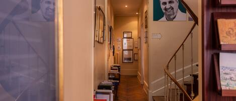 A hallway with bookshelves, framed pictures, and a staircase.