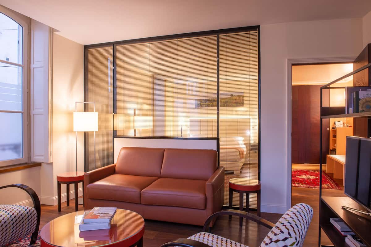 A modern living room with a leather sofa, a glass coffee table, and a bookshelf.