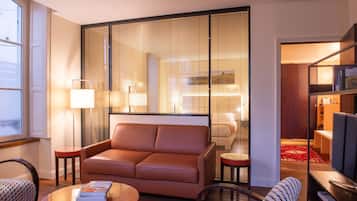 A modern living room with a leather sofa, a glass coffee table, and a bookshelf.