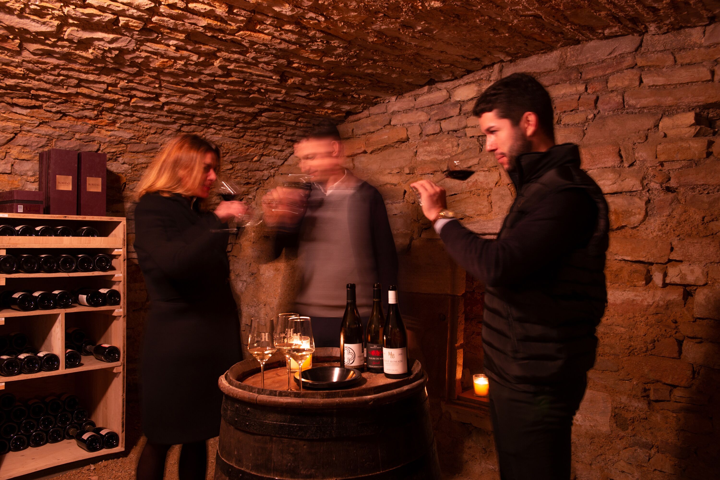 Una bodega rústica con barriles de madera, botellas de vino y una estantería para vinos.