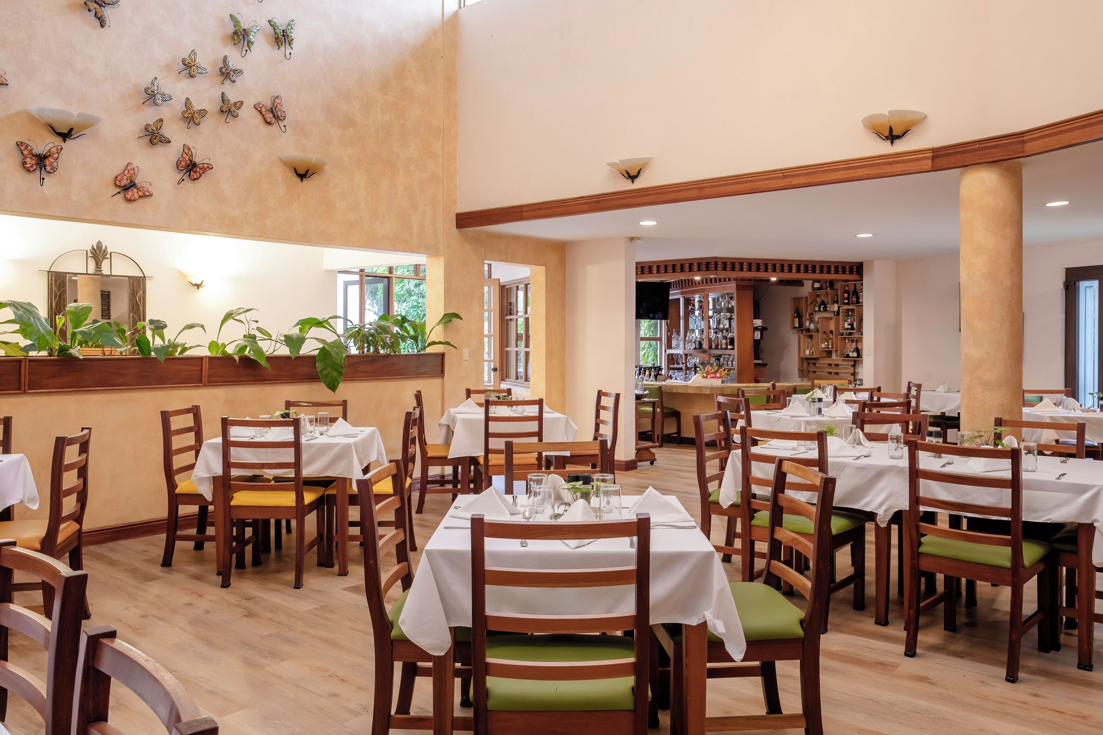 Un restaurante con varias mesas y sillas, una zona de bar y decoración en las paredes.