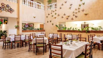 A dining area with multiple tables and chairs, a decorative wall with butterfly wall art, and a ceiling with a light fixture.