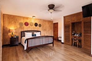A bedroom with a wooden bed, a ceiling fan, a wardrobe, and a desk with a chair. - Buena Vista Chic Hotel (San Isidro)