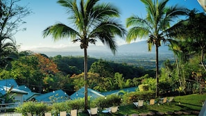 A resort with multiple blue-roofed buildings, palm trees, and a view of a distant cityscape. - Buena Vista Chic Hotel (San Isidro)