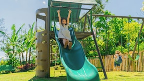 Ein Spielplatz mit einer grünen Rutsche und einer Kletteranlage.