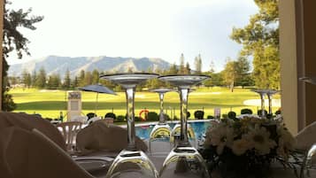 Una mesa preparada para comer con vista a un campo de golf y montañas al fondo.