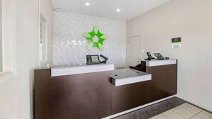 Een receptiebalie met een modern ontwerp, inclusief een geometrische wanddecoratie en een digitaal scherm.