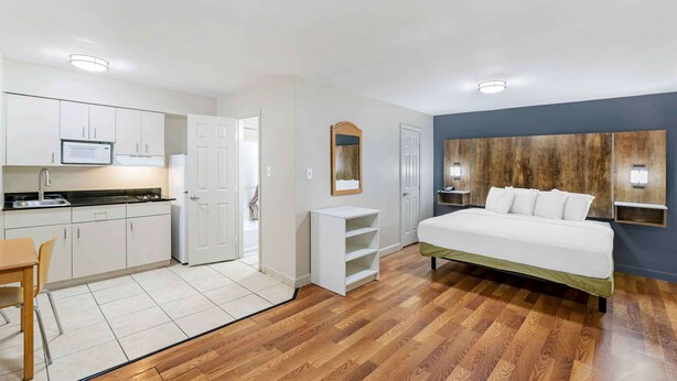 Een compacte hotelkamer met kitchenette, een bed, een klein zithoekje en een spiegel.