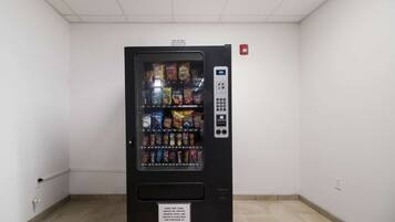 A vending machine in a room with white walls and a tiled floor.