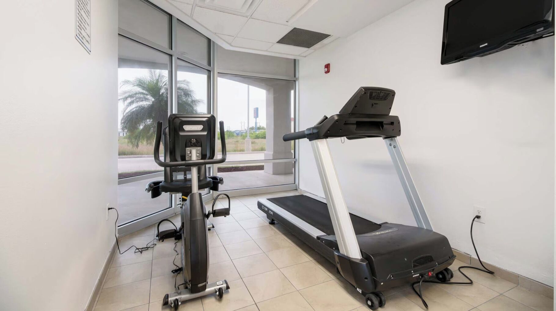 A gym with a treadmill, a stationary bike, and a weight machine.