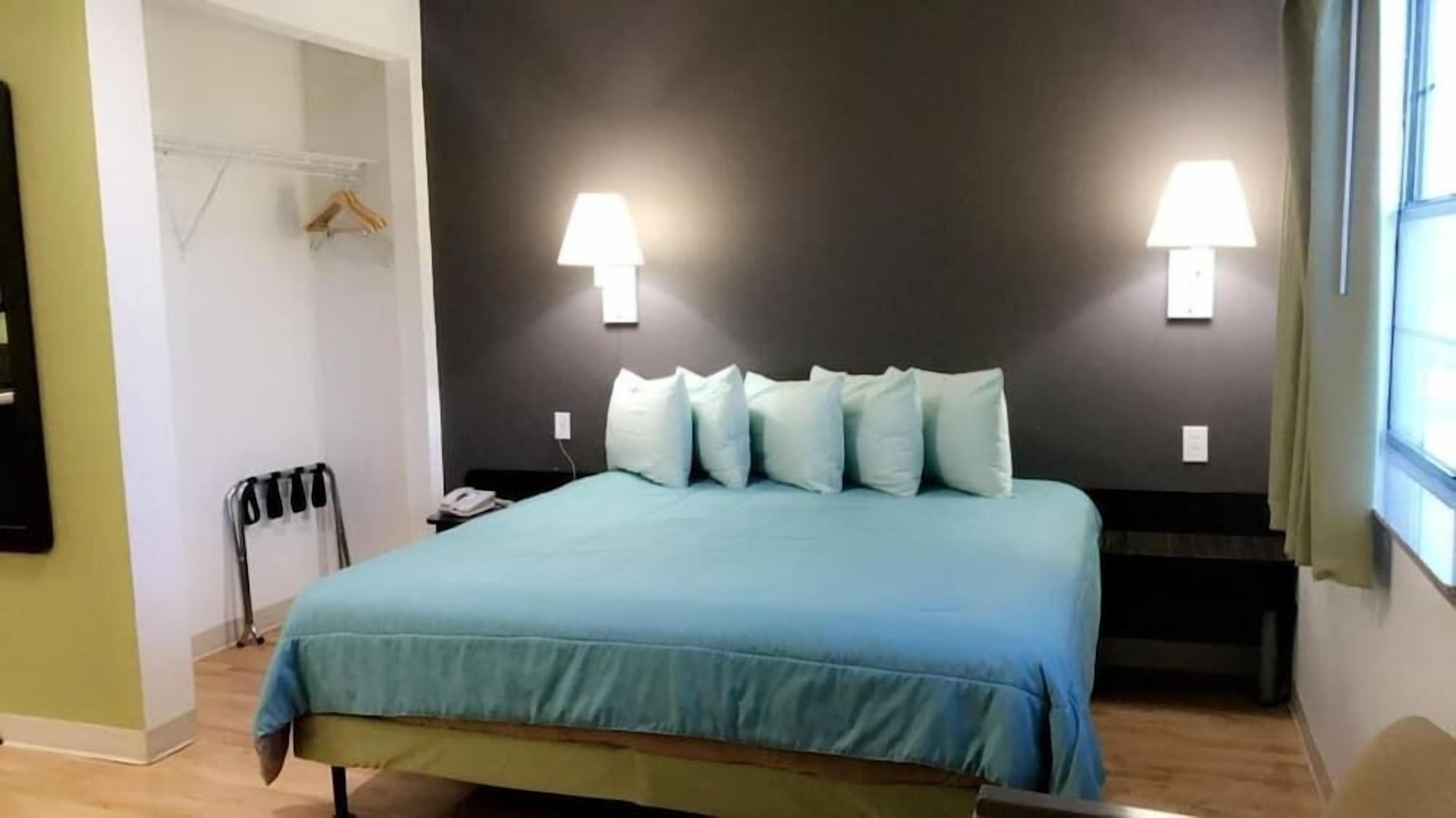 A bedroom with a bed, two bedside lamps, a nightstand, and a window with curtains.