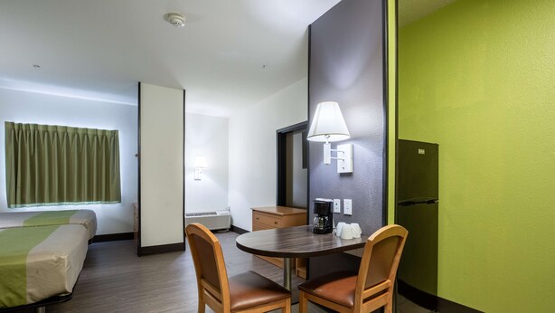 Habitación de hotel con cama, escritorio con silla, cafetera y refrigerador.