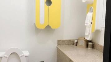A small bathroom with a toilet, a trash bin, a towel dispenser, and a sink.