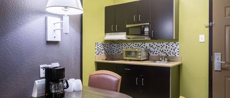 A compact kitchen with a microwave, coffee maker, and a small sink.