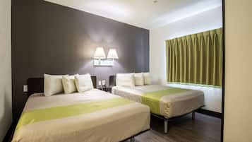 Une chambre d’hôtel avec deux lits, une table de chevet, une lampe et une fenêtre avec des rideaux.