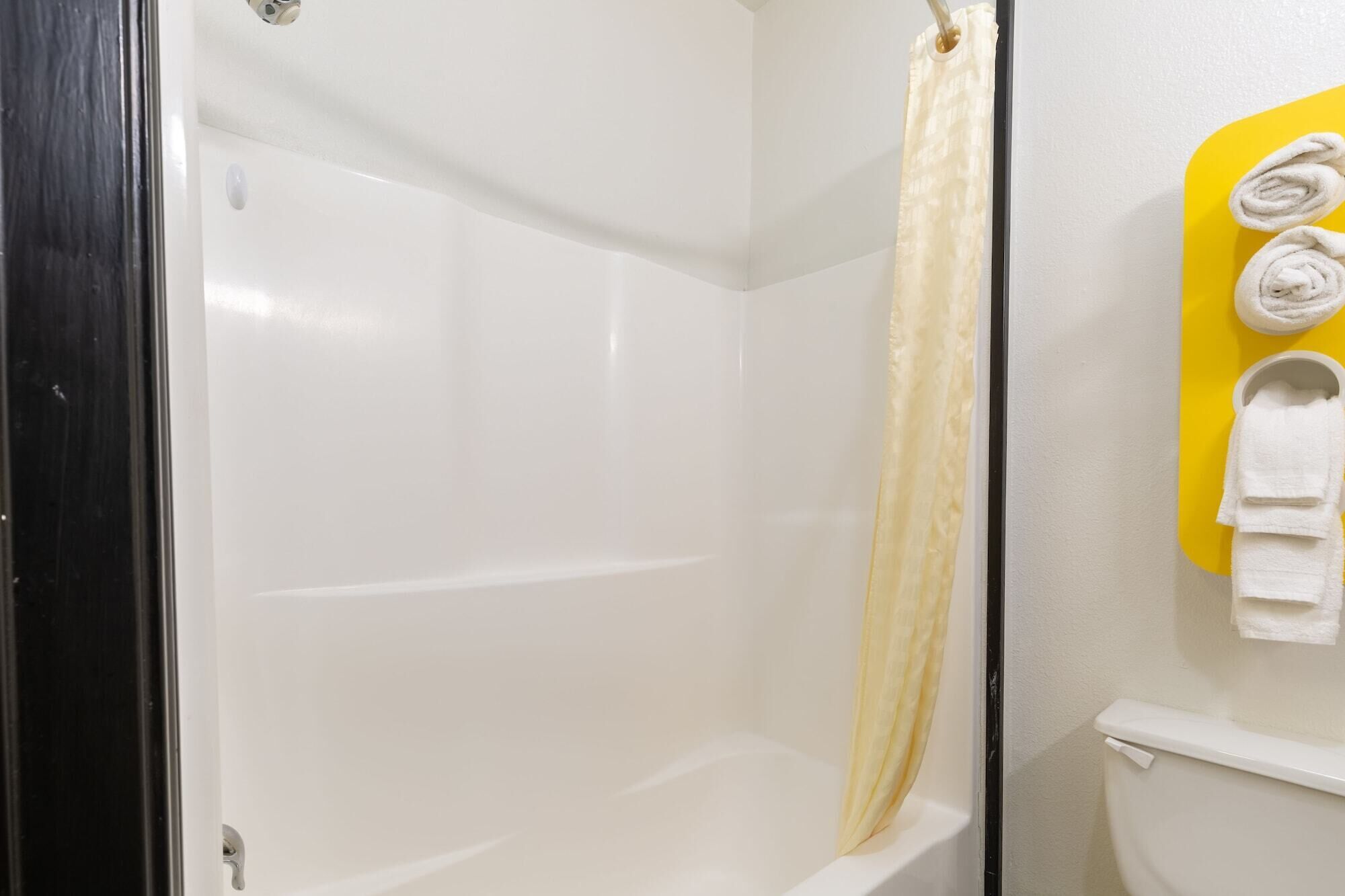 A bathroom with a white bathtub, a yellow towel rack, and a toilet.