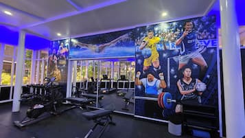 A gym with exercise equipment, a mural with athletes, and large windows.