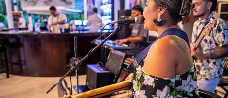 A person playing a guitar at a bar with a microphone stand in front.