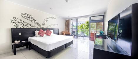 Una habitación de hotel moderna con una cama grande, un televisor de pantalla plana, un escritorio pequeño y un balcón con mobiliario exterior.