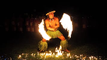 Una persona actuando con fuego en un entorno oscuro al aire libre.