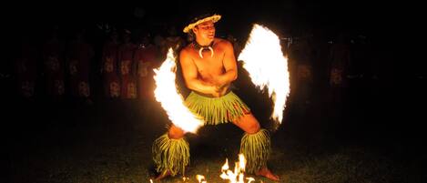 A person performing with fire in a dark outdoor setting.