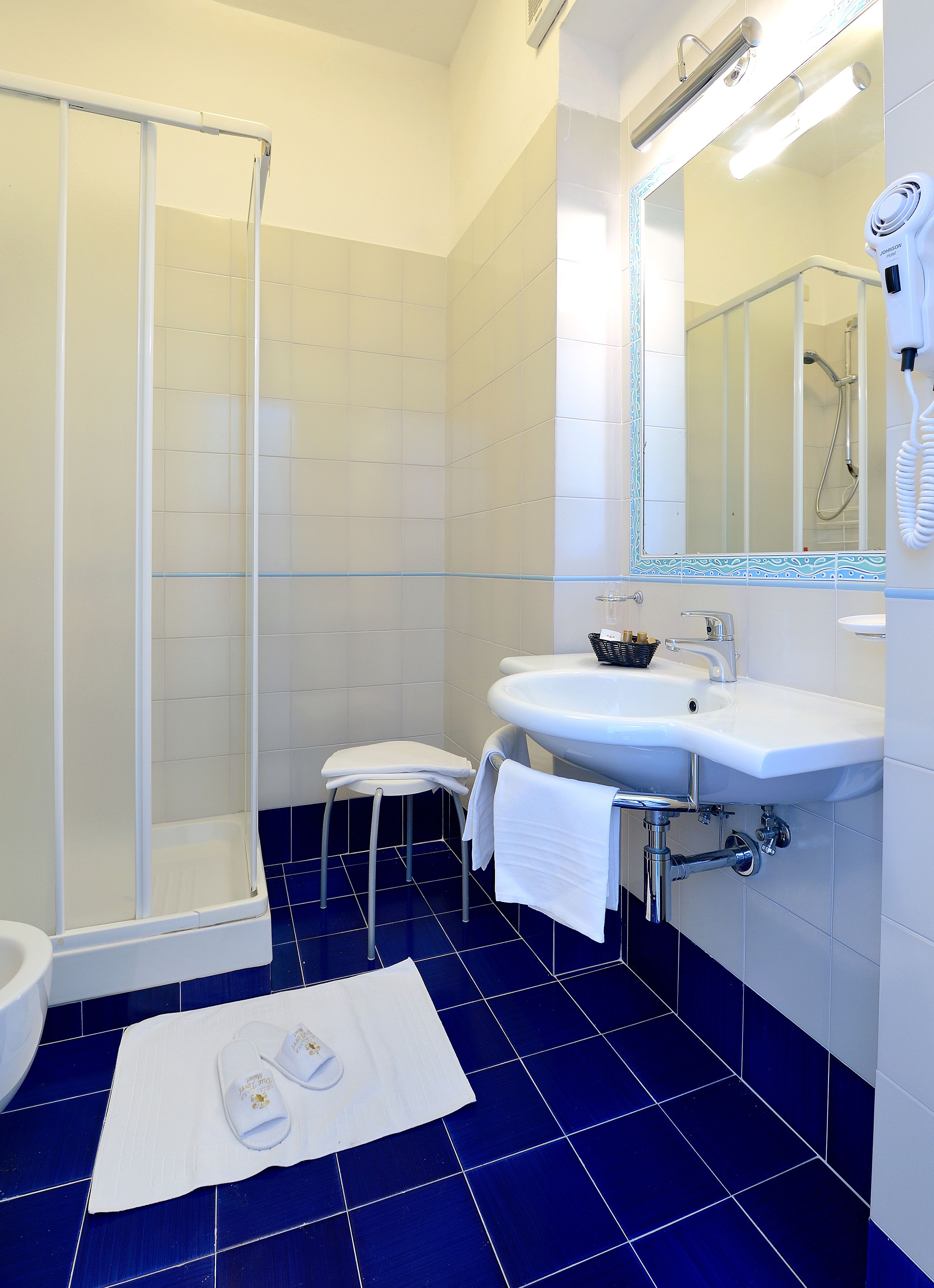 A bathroom with a glass shower enclosure, a white sink, and a mirror above the sink.