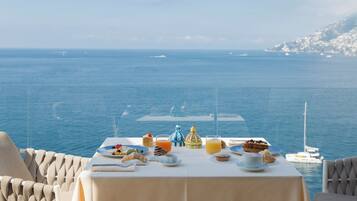 Mesa servida con alimentos para el desayuno con vista al mar.