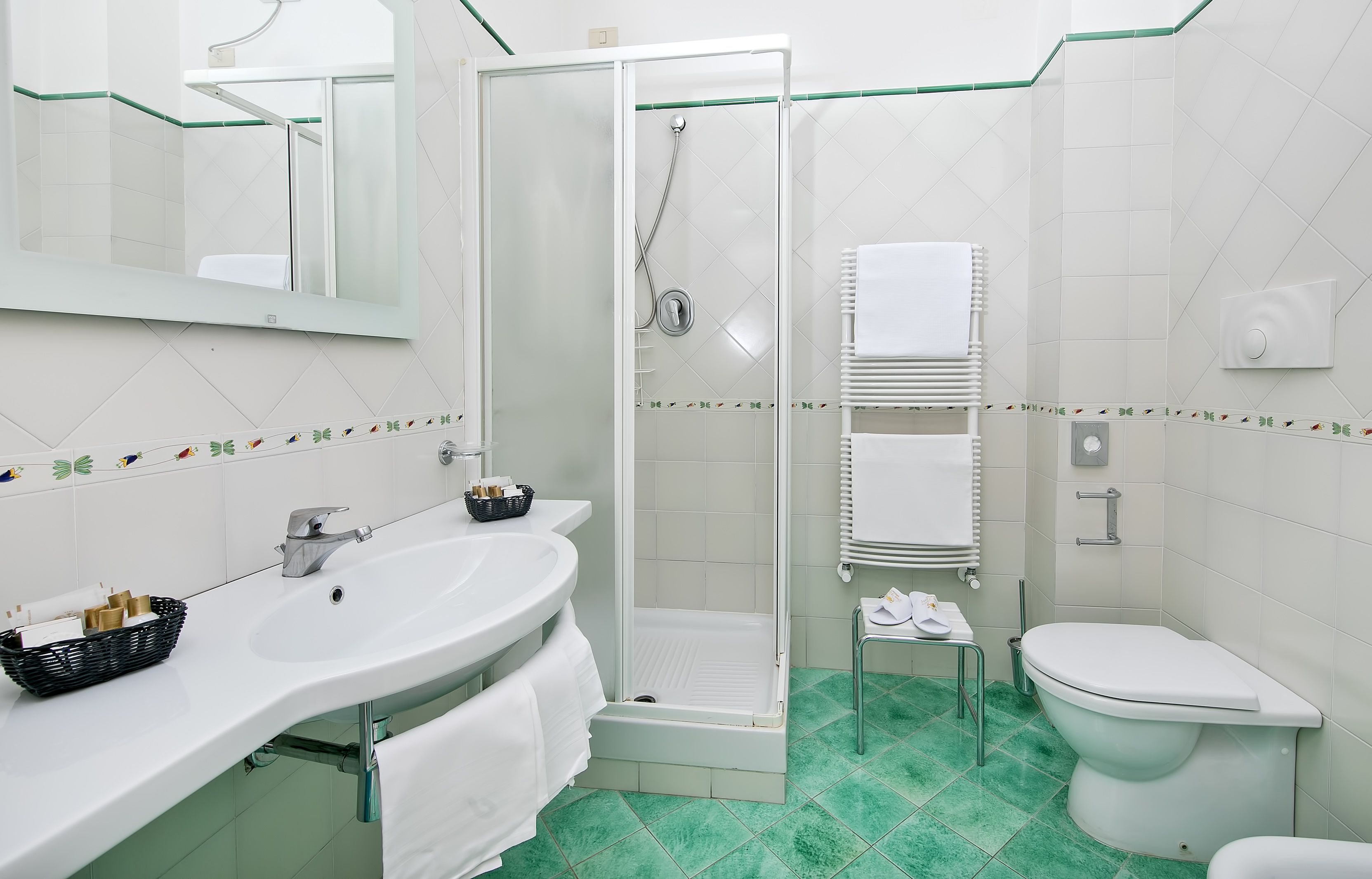 A modern bathroom with a glass-enclosed shower, white sink, and toilet.
